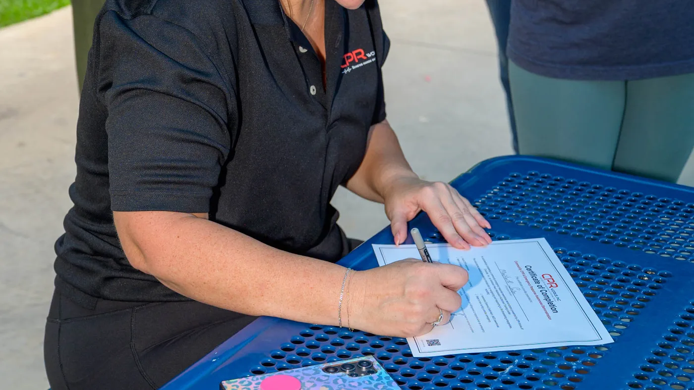 A CPR Works instructor filling out and signing course completion paperwork at the training table