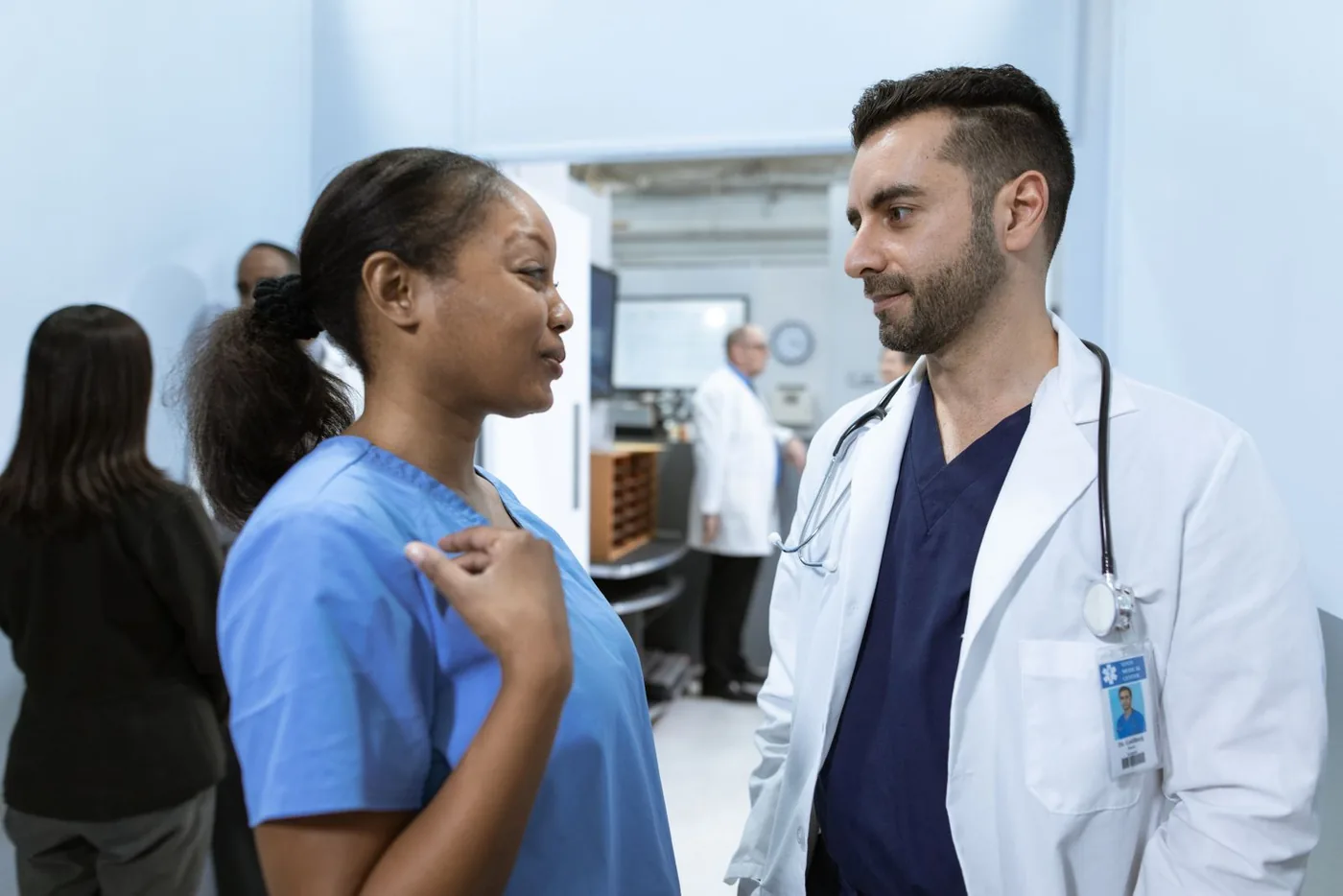 A nurse and a physician talk through a patient's care in a hospital corridor